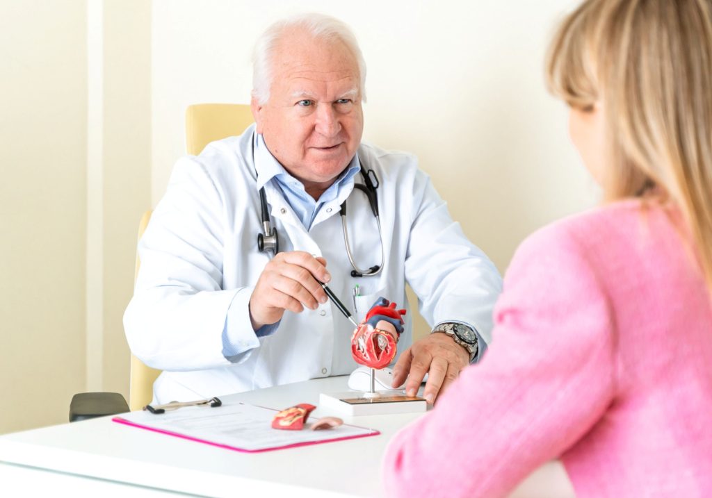 Dr n. med. Andrzej Sieńko podczas konsultacji kardiologicznej w Centrum Medycznym neoMedica w Poznaniu wskazuje na model serca.