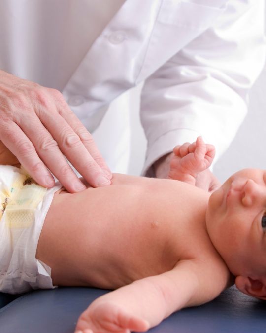 Lekarz badający brzuszek noworodka - ilustracja dotycząca USG jamy brzusznej dziecka w Centrum Medycznym neoMedica w Poznaniu.