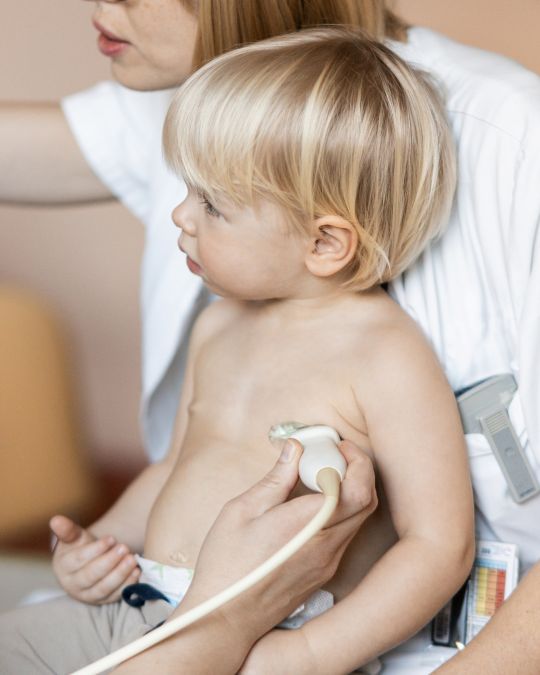 Głowica USG przykładana do klatki piersiowej dziecka na kolanach mamy - ilustracja dotyczy badania echo serca dzieci w Centrum Medycznym neoMedica w Poznaniu.