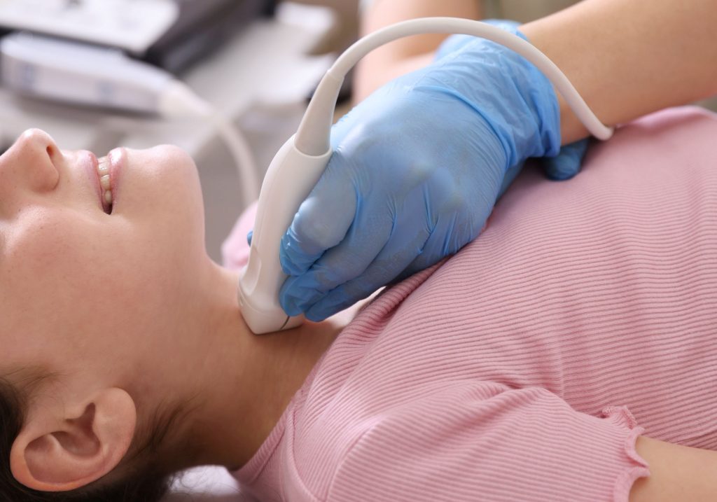 Lekarz w rękawiczkach lekarskich przykłada głowice USG do szyi dziecka - ilustracj dotycząca USG tarczycy u dzieci w Centrum Medycznym neomedica w Poznaniu.